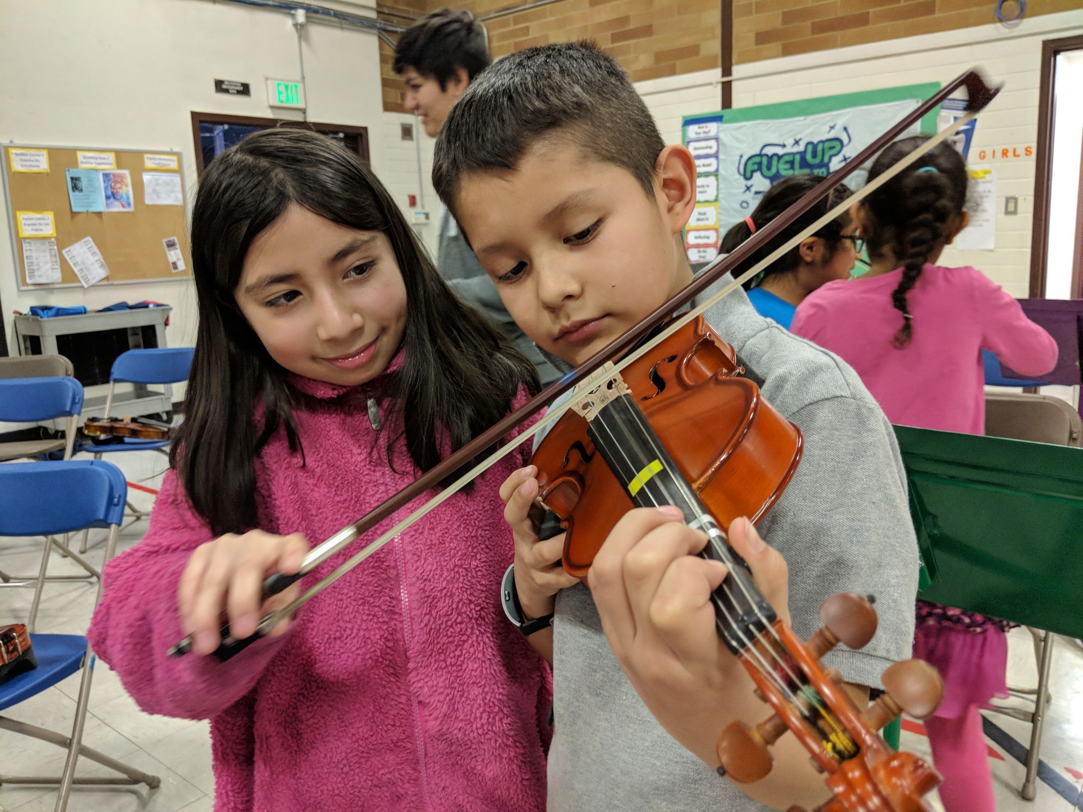 Boy and girl playing a violin together